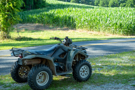Green off-road vehicle in foreground with agricultural cornfield